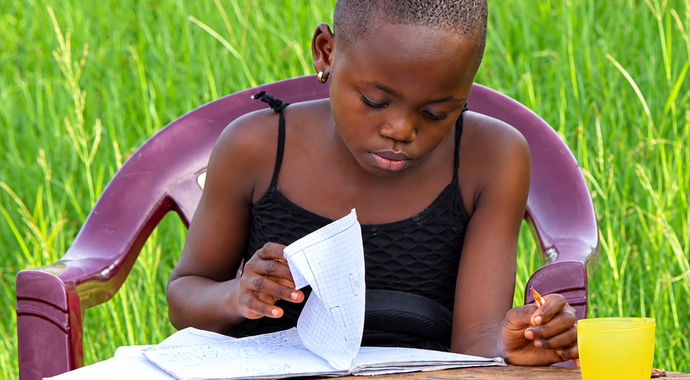 Children studying outdoors with their school supplies